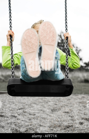 Bambina su uno swing presso il parco giochi. Foto Stock