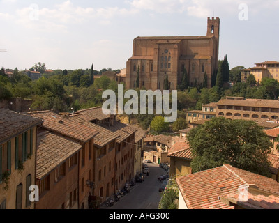 Strada stretta con edifici residenziali e motorscooters e San Domenico nel retro Siena Italia Foto Stock