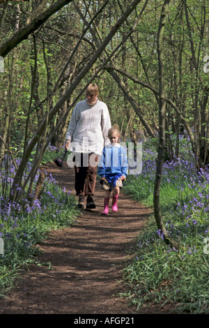 Madre e figlia giovane passeggiate attraverso boschi bluebell East Sussex Foto Stock