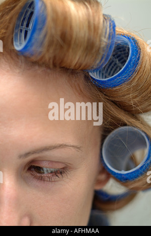 Rulli in i capelli di una giovane donna, vicino. Foto Stock