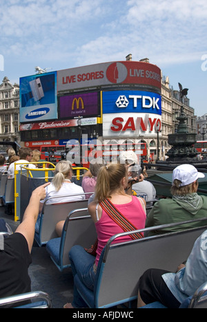 Londra passeggeri a bordo ponte superiore di open top sightseeing tour bus con turisti viste verso Piccadilly Circus & Eros con un cartellone pubblicitario REGNO UNITO Foto Stock