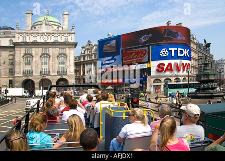 Londra passeggeri a bordo ponte superiore di open top sightseeing tour bus con turisti viste verso Piccadilly Circus & Eros con un cartellone pubblicitario REGNO UNITO Foto Stock
