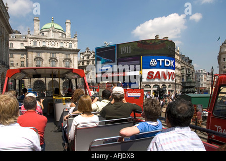 Londra passeggeri a bordo ponte superiore di open top sightseeing tour bus con turisti viste verso Piccadilly Circus & Eros con un cartellone pubblicitario REGNO UNITO Foto Stock