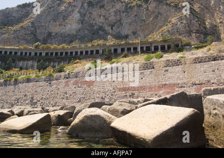 Cava di blocchi di pietra di un mattone parete di ritegno un treno tunnel e una collina visto dalla Baia di Isola Bella a Taormina Italia sulla Sicilia Foto Stock