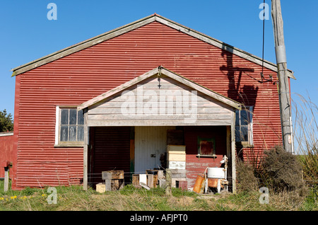 Un vecchio edificio di legno con junk impilati davanti al suo ingresso. Foto Stock