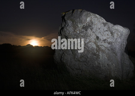 La preistorica Longstones (Adamo ed Eva) illuminate di notte di luna piena sorgere in background, Avebury, Wiltshire, Inghilterra, Regno Unito Foto Stock