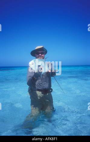 Uomo permettono di contenimento dei pesci catturati durante la pesca con la mosca in Belize Caraibi Modello rilasciato Image Foto Stock