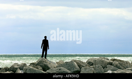 Silhouette di un giovane uomo in piedi sulle rocce sul lungolago del Lago Michigan Foto Stock
