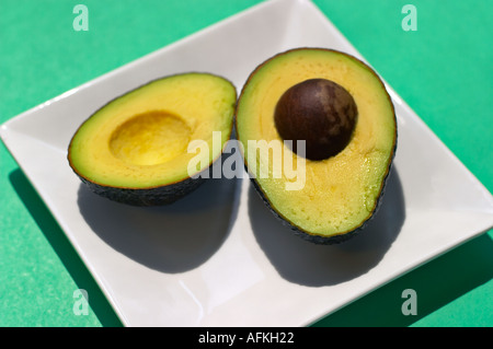 Cartolina-grafico stile colpo di fette di avocado sul quadrato bianco piastra, sfondo verde. Foto Stock
