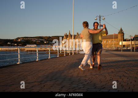 Medio - età giovane ballare il valzer o tango in serata sul lungomare a Aberystwyth Ceredigion nel Galles Foto Stock