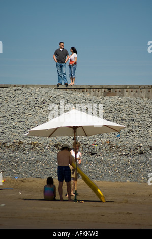 La gente sulla spiaggia sotto un ombrellone bianco Ynyslas beach e sabbie, Borth Ceredigion nel Galles Foto Stock