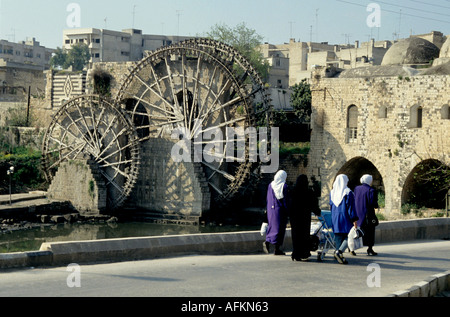 Il gruppo di donne a piedi da un waterwheel sul fiume Oronte, Hama, Siria. Foto Stock