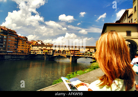 Ponte Vecchio oltre il fiume Arno con una femmina giovane turista la lettura di una guida turistica Prenota Italia Firenze Toscana Europa scenic Ponte Foto Stock