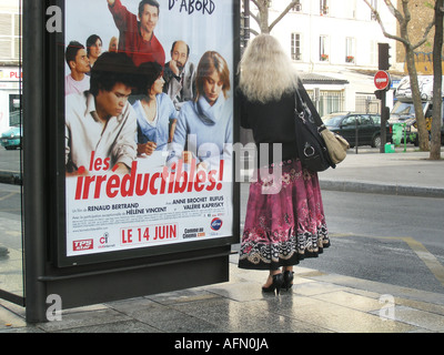 Donna con i capelli grigi vestito di lunga gonna e giacca in attesa presso un parigino di fermata bus Parigi Francia Foto Stock