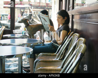 Giovane donna caucasica e il suo cane in attesa per un drink a Parisian lato strada cafe terrazza Francia Foto Stock