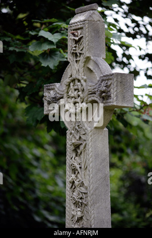 Croce celtica in un cimitero con decorazioni floreali su di esso Foto Stock