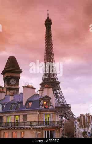 Giovane seduto in appartamento al secondo piano nella finestra di Parigi al tramonto Foto Stock