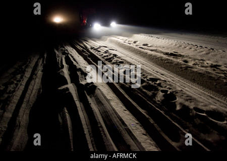 I veicoli fuoristrada l'illuminazione di una strada di sabbia con i suoi fari anteriori Foto Stock