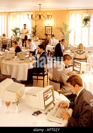 Un pranzo di lavoro, UFFICIO LAVORATORI AVENTI UN COMPUTER PER IL PRANZO IN UN RISTORANTE DI PAUSA PRANZO Foto Stock