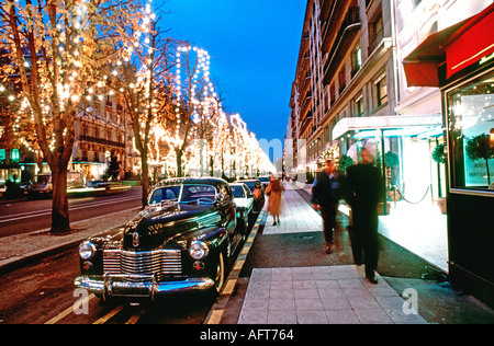 Natale a Parigi Francia Ave Montaigne Street Scene 'Lit Up' di notte con Holiday luci di natale Shopping Auto di lusso, auto di strada vintage parigi Foto Stock