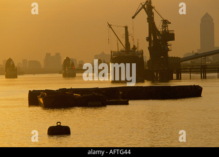 Thames Flood Barrier Canary Wharf Canada Square building London UK 1990 1991 Gru di carico nave che lavora sul fiume Tamigi chiatte OMERO SYKES Foto Stock