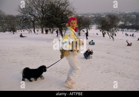 Donna di mezza età alla moda che cammina un cane che porta un altro sulla neve a Primrose Hill, Londra, Inghilterra, anni '1991 1990 UK HOMER SYKES Foto Stock