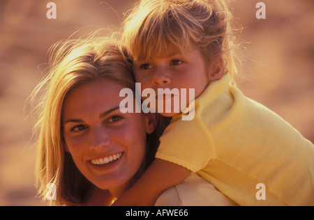 Close up ritratto della madre che porta la sua giovane figlia sovrapponibile all'aperto su una calda giornata Foto Stock