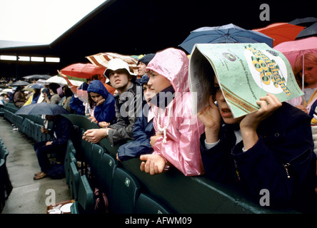 Wimbledon tennis Londra SW19 1980s Regno Unito. La pioggia smette di giocare i tifosi in attesa della ripresa della partita sul campo centrale. Il programma era diretto da Rain 1985 Foto Stock