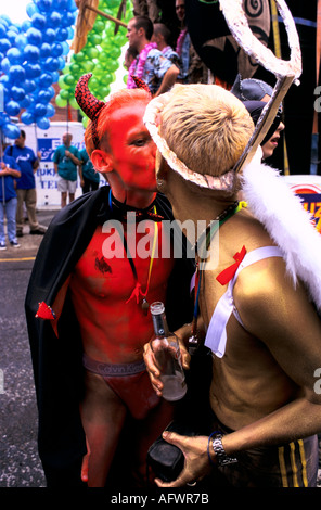 Manchester Pride Festival 1990s Gayfest UK LGBT due uomini vestiti da diavolo e angelo si baciano durante la sfilata della città. 1999 Inghilterra Foto Stock