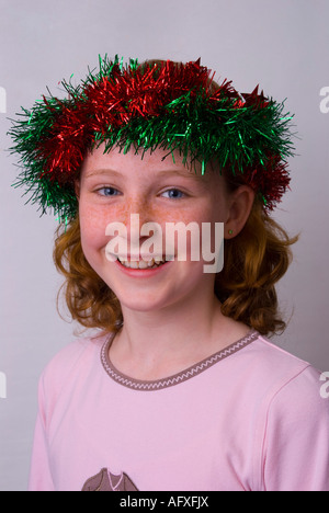 Un sorridente dagli occhi blu di fronte freckle 11 anno vecchia ragazza di origine irlandese indossando orpelli natalizi in her hair Foto Stock