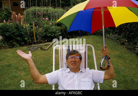 Bill Giles meteorologi di BBC seduto sulla sedia a sdraio con ombrellone in giardino guardando il cielo HOMER SYKES Foto Stock