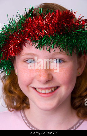 Un sorridente dagli occhi blu di fronte freckle 11 anno vecchia ragazza di origine irlandese indossando orpelli natalizi in her hair Foto Stock