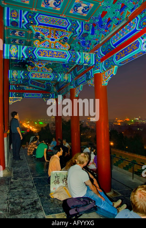 Pechino, CINA, turisti in visita ad un antico Monumento colorato il 'Wanchun Pavillon' che si affaccia di notte, rilassandosi in un giardino moderno Foto Stock