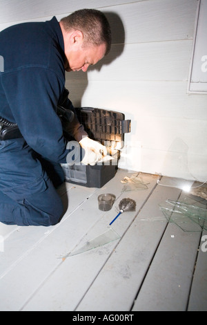 Investigatore della scena del crimine alla ricerca di impronte digitali sulla scena di un furto con scasso. Foto Stock