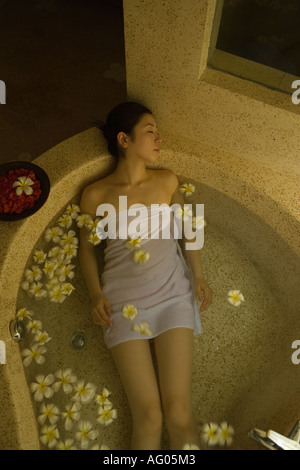 Giovane donna tenendo bagno con petali di fiori Foto Stock