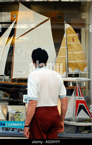 Un anziano pensionato uomo gentleman guardando al modello racing yachts in una finestra del negozio durante la cowes week sull'isola di Wight Foto Stock