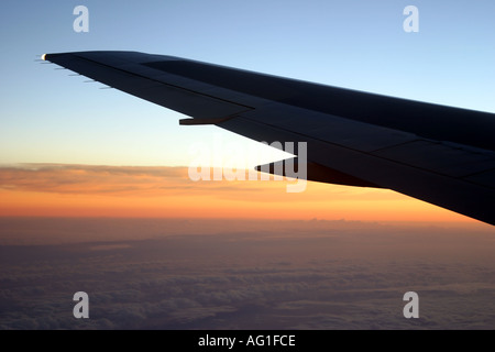 Ala di aeroplano in volo durante il sunrise Foto Stock