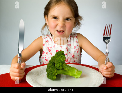 Ragazza giovane non è contento di dover mangiare broccoli Foto Stock