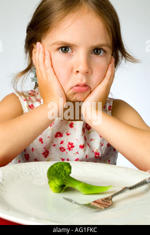 Ragazza giovane non è contento di dover mangiare broccoli Foto Stock