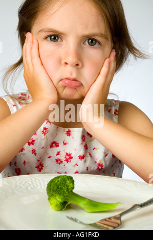 Ragazza giovane non è contento di dover mangiare broccoli Foto Stock