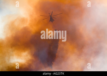 Helicpoters scontri a fuoco di montagna utilizzando acqua bombe battenti in e attraverso il denso fumo e fiamme alte Foto Stock