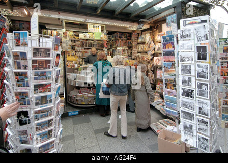 Gente di Parigi lo shopping al tipico cartolina carta per riviste e giornali di stallo kiosk sul marciapiede con il fornitore che serve i clienti di Francia Foto Stock