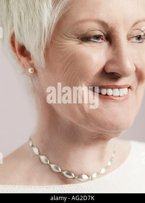 Donna di mezza età cercando di lato e sorridente, close-up (ritagliate) Foto Stock