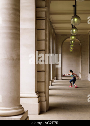 Atleta femminile gettando discus nel portico, vista laterale Foto Stock