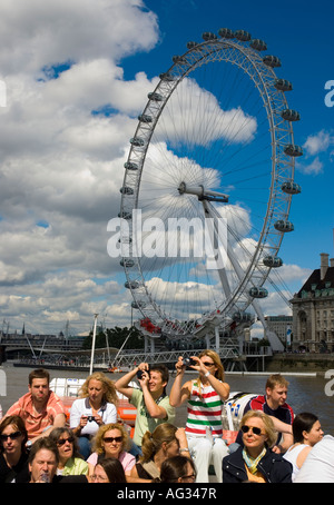 La gente guarda le case del parlamento da una gita in barca sul fiume Tamigi con la London Eye in background Foto Stock