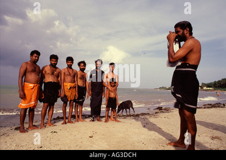 Un uomo indiano scatta una foto dei suoi amici a. La spiaggia della città di Rameswaram si trova sull'isola di Pamban in Tamil Nadu India del Sud Foto Stock