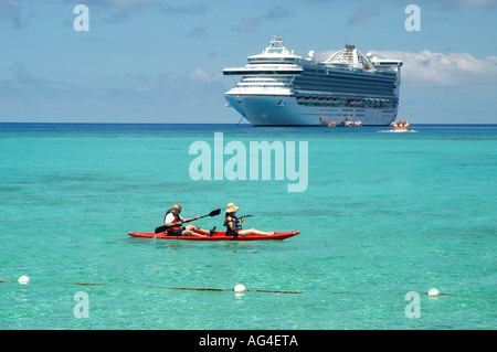 La nave di crociera che sono ancorate al largo di un'isola deserta nel Mar dei Caraibi, con una canoa in primo piano. Foto Stock