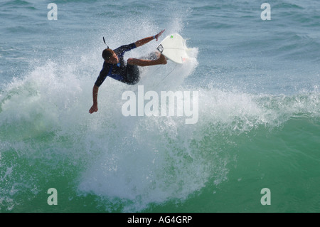 Un surfista eseguendo una manovra di antenna su onde in Huntington Beach California Foto Stock