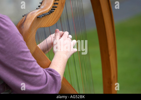 Le mani della giovane donna giocando un arpa in legno in un parco pubblico a Belfast Foto Stock