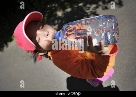 In prossimità di una giovane ragazza di bere acqua da una bottiglia di plastica Foto Stock